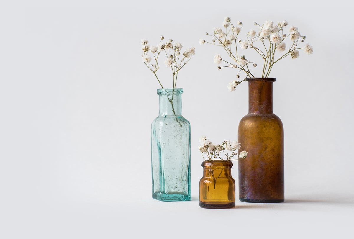 Alte Glasflaschen in braun und hellgrün mit Blumen